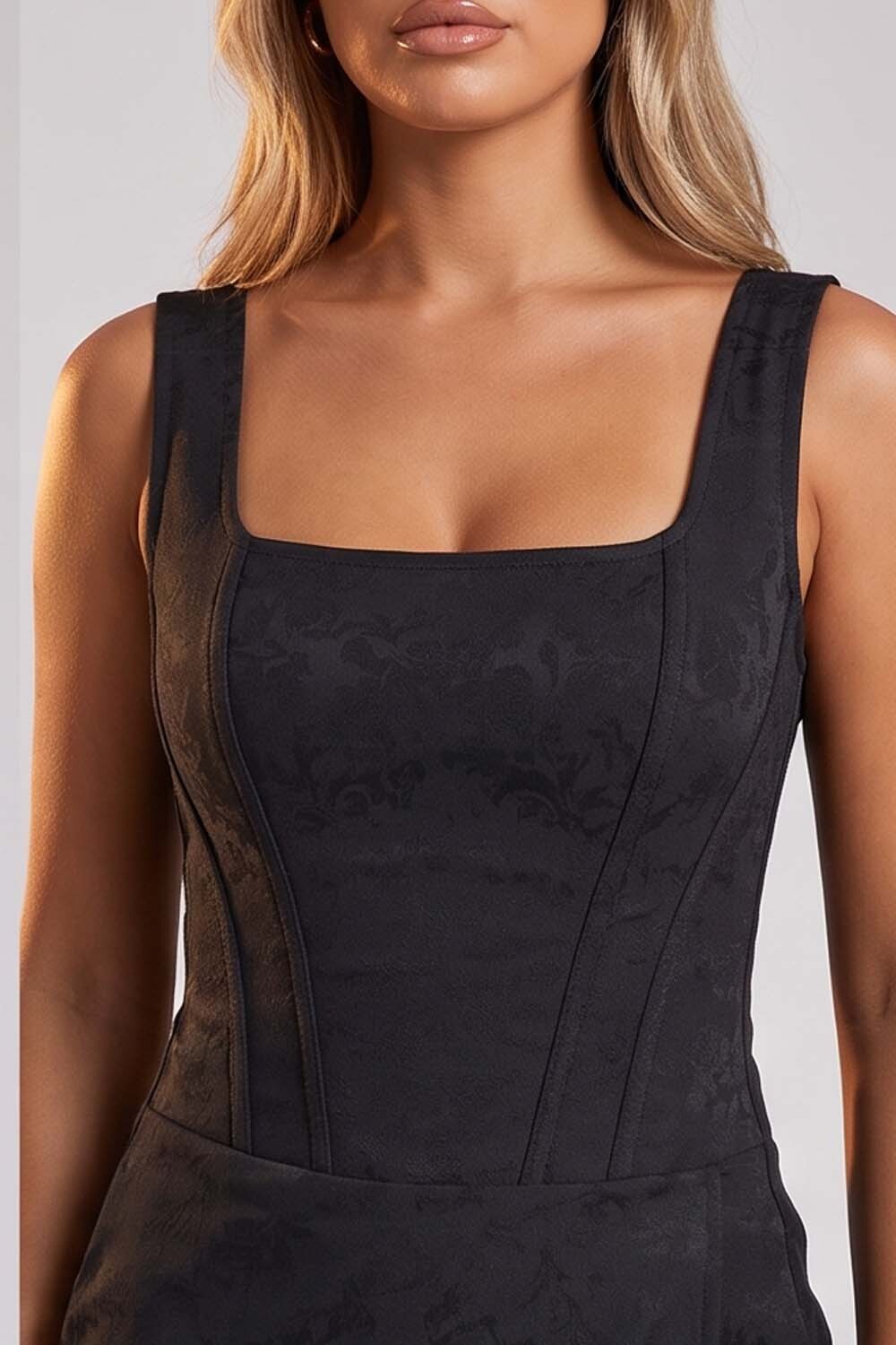 A close-up of a model wearing a black Luxe Noir Corset Skort   with a square neckline and subtle tonal jacquard pattern.